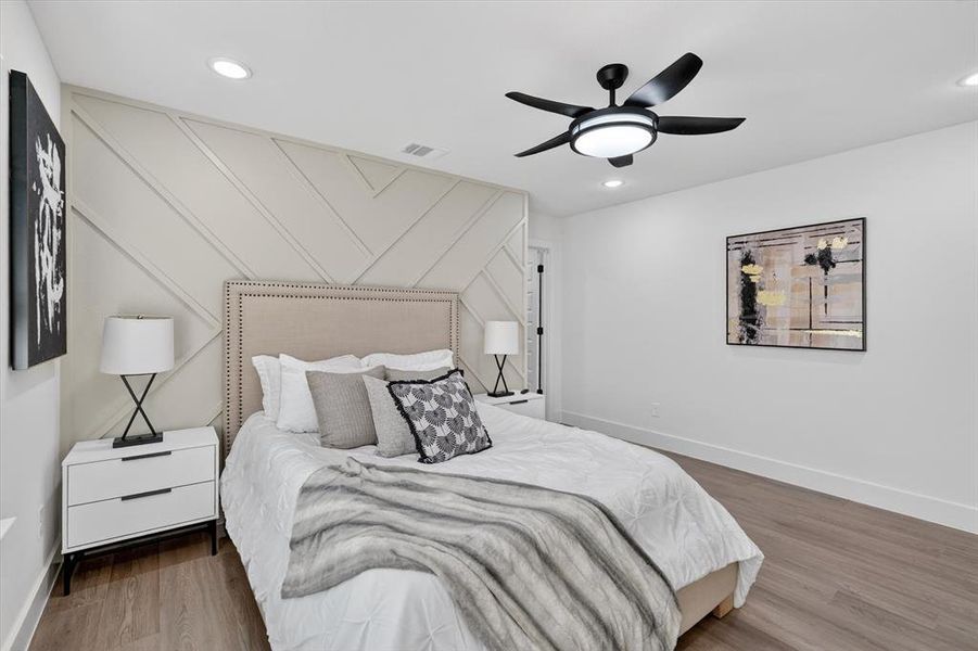 Interior room featuring a geometric accent wall, wood-finish flooring, recessed lighting, a ceiling fan with light, and white baseboards
