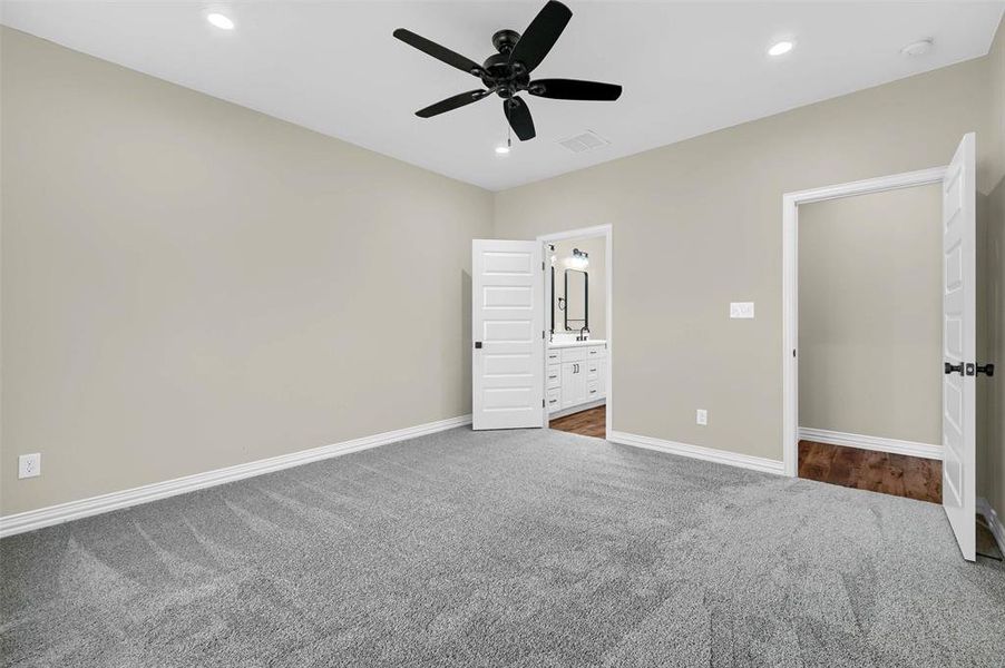 Unfurnished bedroom featuring connected bathroom, carpet floors, and ceiling fan