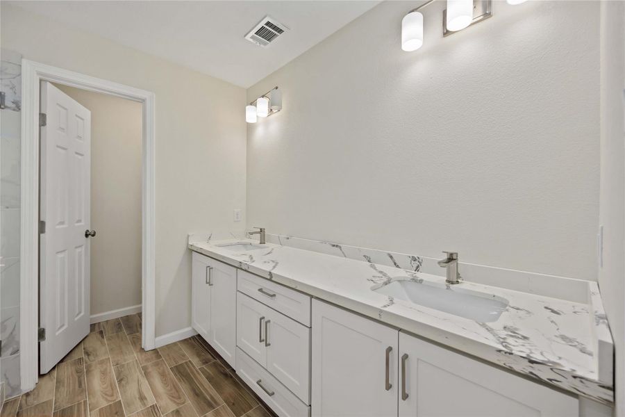 Primary bathroom featuring double sinks, modern fixtures, and a sleek design.