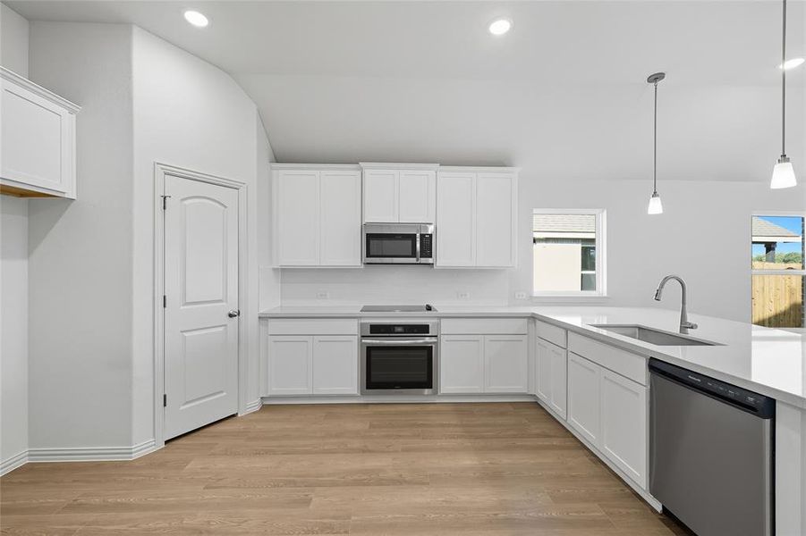 Kitchen featuring white cabinets, appliances with stainless steel finishes, lofted ceiling, and recessed lighting Kitchen featuring white cabinets, appliances with stainless steel finishes, lofted ceiling, and recessed lighting