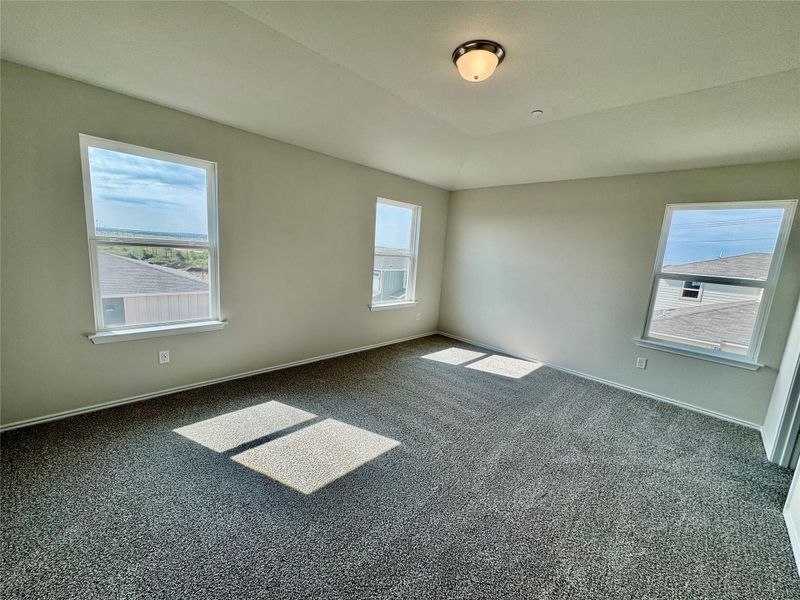 Unfurnished room with carpet floors, plenty of natural light, and lofted ceiling Unfurnished room with carpet floors, plenty of natural light, and lofted ceiling