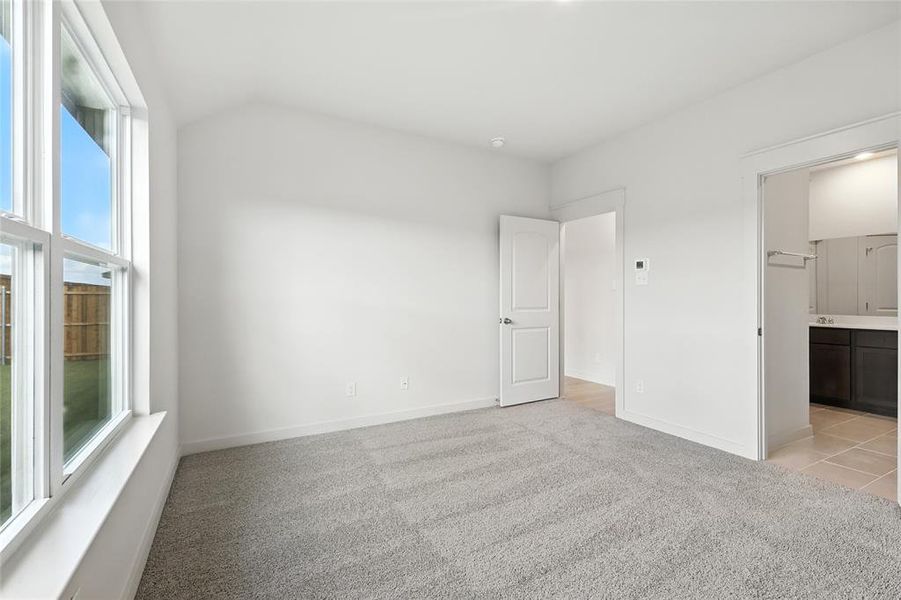 Unfurnished bedroom with light carpet, ensuite bathroom, and lofted ceiling Unfurnished bedroom with light carpet, ensuite bathroom, and lofted ceiling