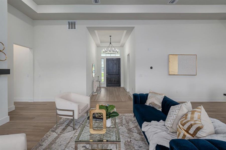 Living room featuring a tray ceiling, wood-type flooring, and a chandelier