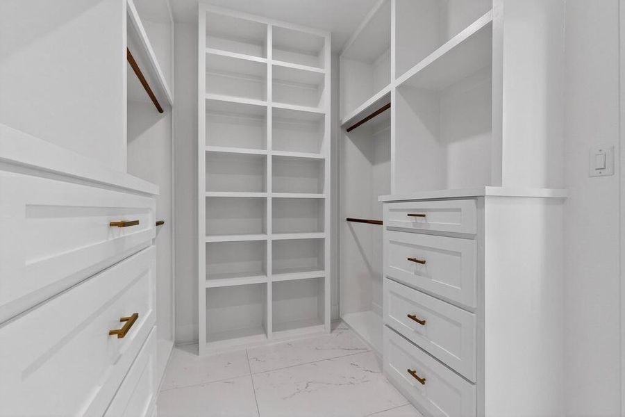 Walk in closet featuring light marble finish flooring