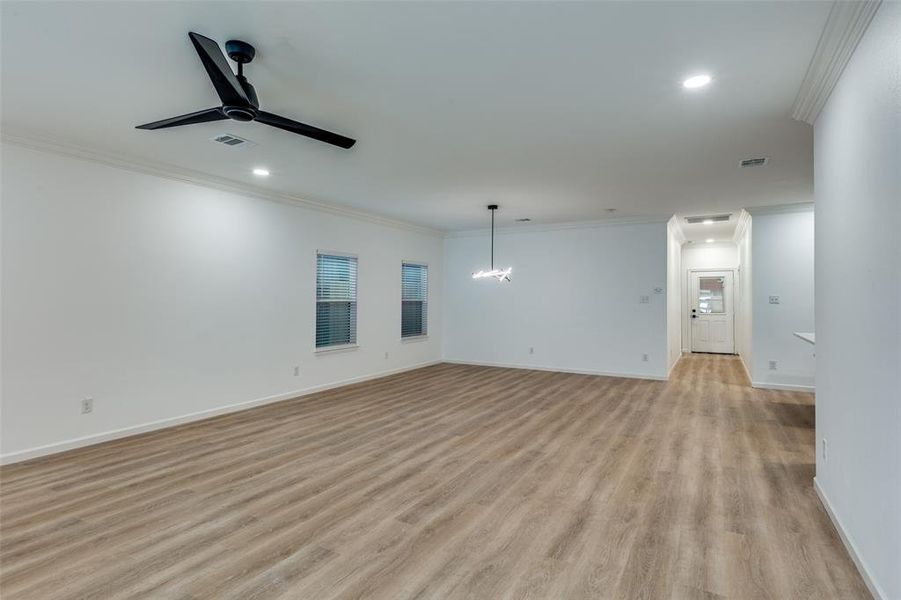 Unfurnished living room featuring crown molding, ceiling fan, light wood-style floors, recessed lighting, and a chandelier Unfurnished living room featuring crown molding, ceiling fan, light wood-style floors, recessed lighting, and a chandelier