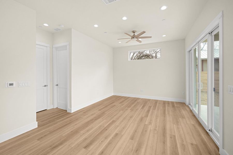 Spacious living room with sliding doors that lead to the extensive back patio on the right. On your left, a bedroom and a full bathroom.