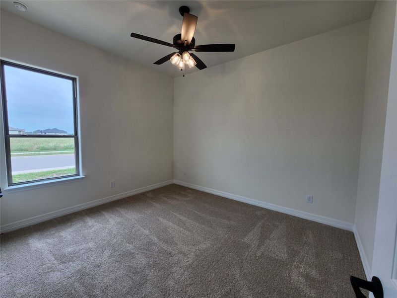 Neutral-toned walls and plush carpeting in this room with a ceiling fan light fixture