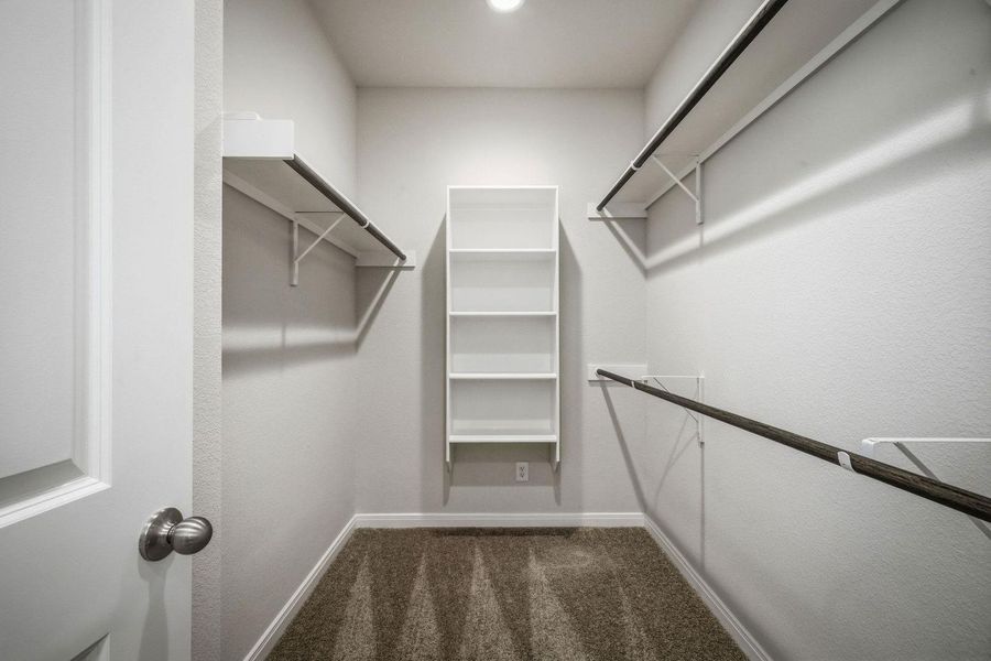 Ample hanging rods and built-in shelving maximize storage space in this carpeted closet. Ample hanging rods and built-in shelving maximize storage space in this carpeted closet.