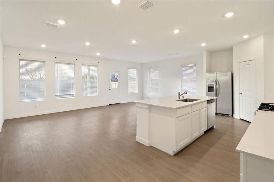 Kitchen featuring an island with sink, light wood finished floors, stainless steel appliances, open floor plan, and recessed lighting