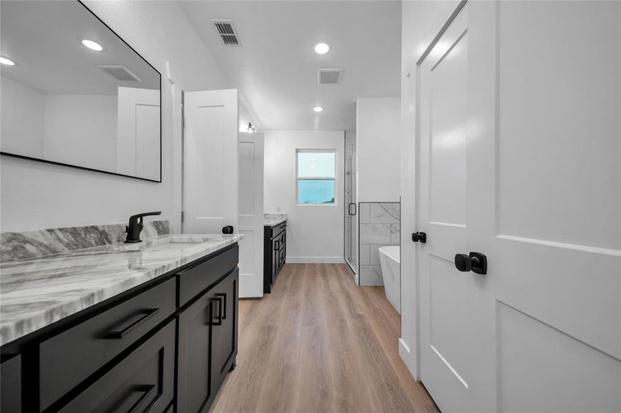 Bathroom with hardwood / wood-style flooring, vanity, and separate shower and tub