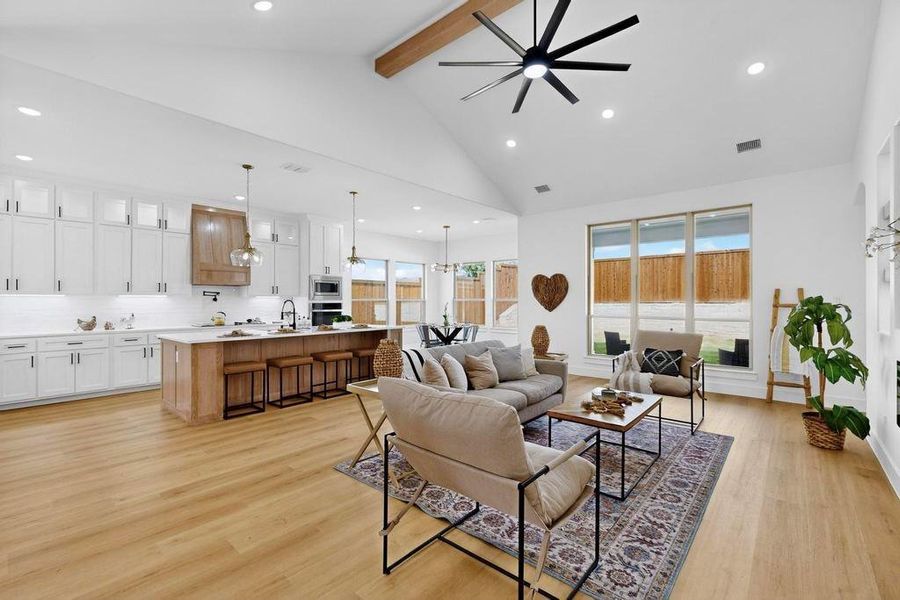 Living area with recessed lighting, light wood-style floors, beamed ceiling, high vaulted ceiling, and ceiling fan