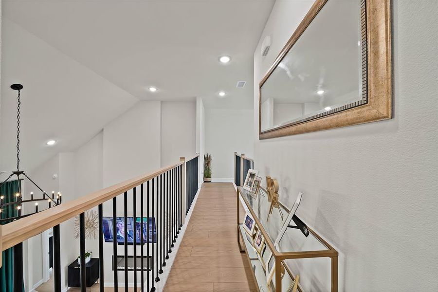 Upper-level hallway with wood-finish flooring, recessed lighting, and a wrought iron and wood handrail Upper-level hallway with wood-finish flooring, recessed lighting, and a wrought iron and wood handrail