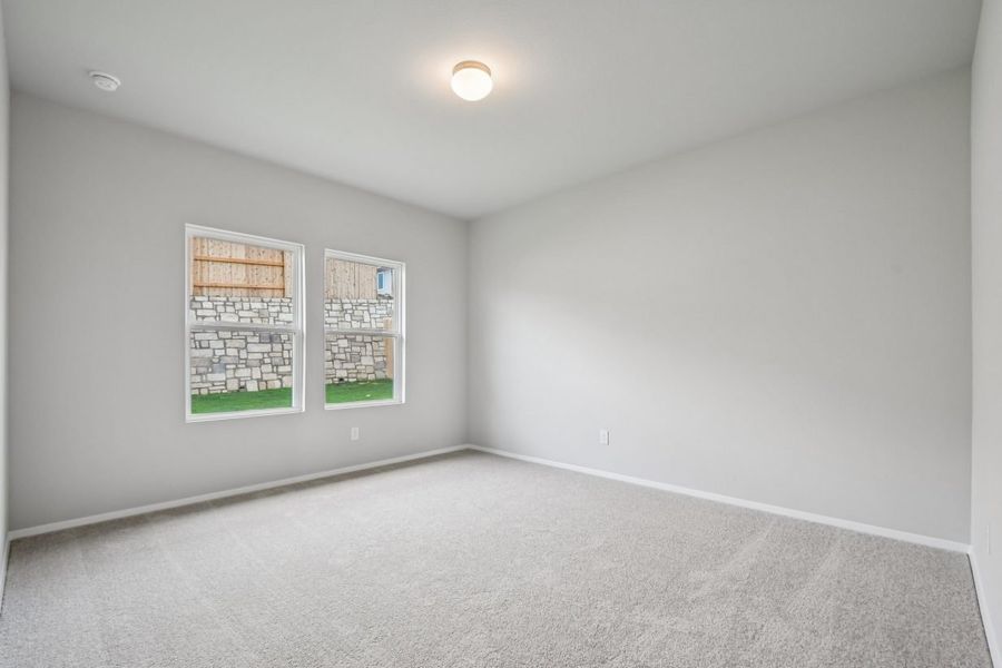 Primary bedroom with large windows, grey walls and tan carpeting