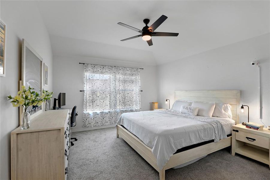 Carpeted bedroom with ceiling fan and lofted ceiling