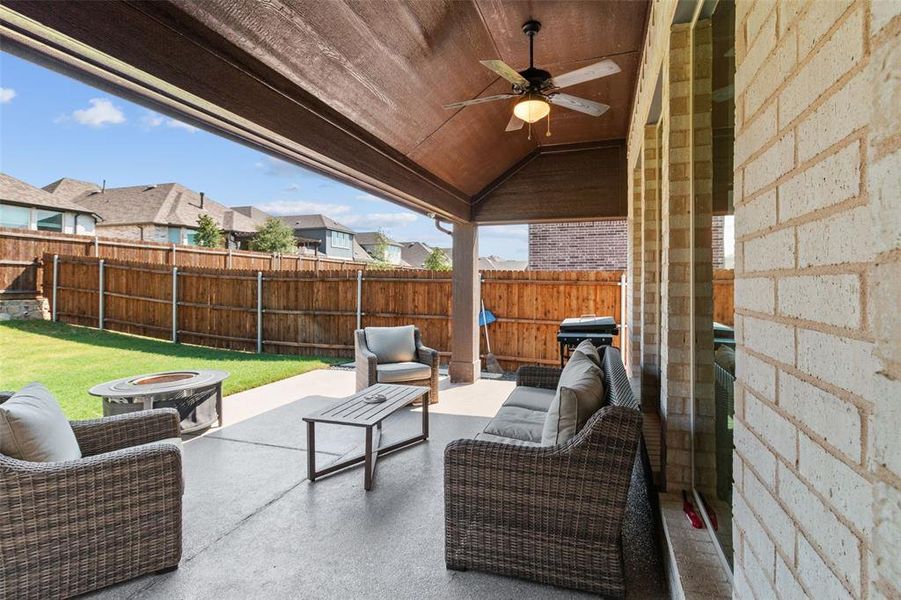 Fenced backyard with a patio, an outdoor living space with a fire pit, and ceiling fan