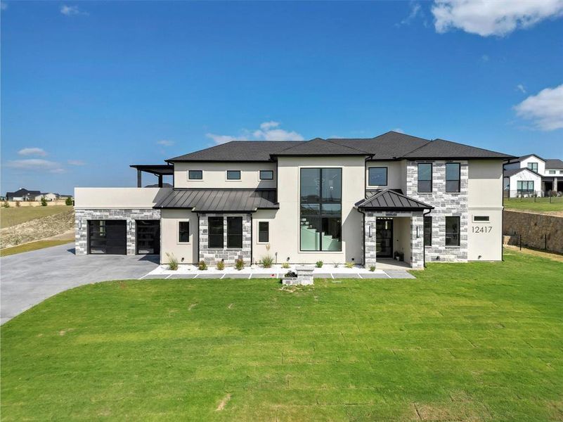 Rear view of property featuring a garage and a lawn