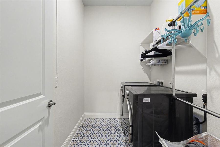 Laundry area featuring patterned tile flooring, white baseboards, and bright white walls