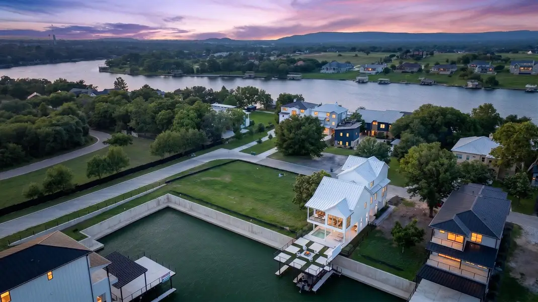 An aerial perspective reveals a serene waterfront community at twilight, with homes nestled along the lake and a private boat dock. An aerial perspective reveals a serene waterfront community at twilight, with homes nestled along the lake and a private boat dock.