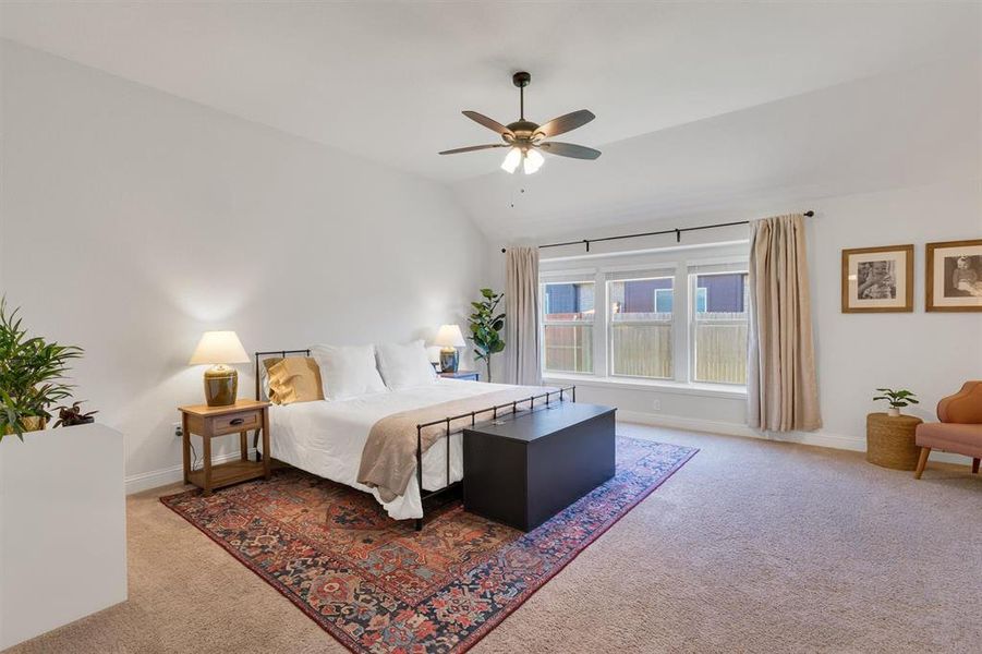 Carpeted bedroom with ceiling fan and vaulted ceiling