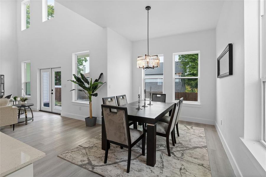 Dining room featuring light wood finished floors, a chandelier, french doors, and a high ceiling Dining room featuring light wood finished floors, a chandelier, french doors, and a high ceiling