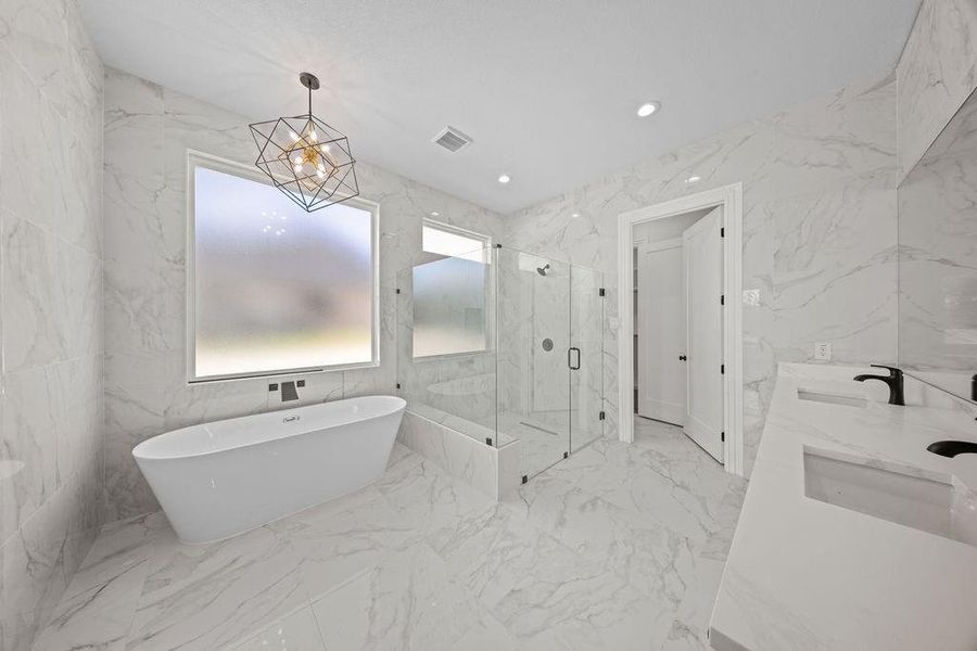 Full bath with a marble finish shower, double vanity, recessed lighting, a freestanding bath, and stone wall