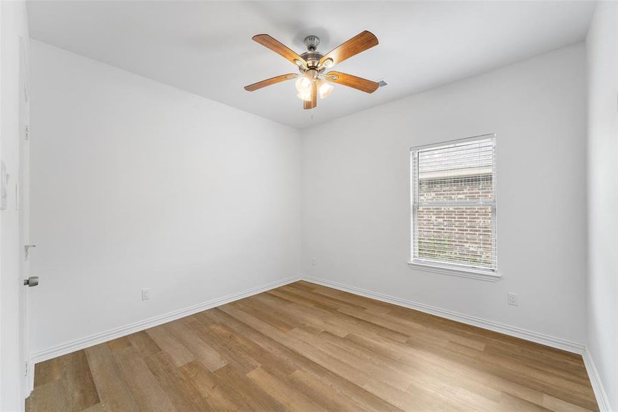 Room featuring wood-finish flooring, white baseboards, a ceiling fan with integrated lighting, and a window with blinds