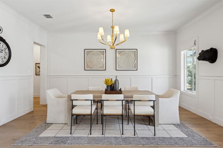 Dining area featuring ornamental molding, light wood-type flooring, visible vents, and an inviting chandelier Dining area featuring ornamental molding, light wood-type flooring, visible vents, and an inviting chandelier