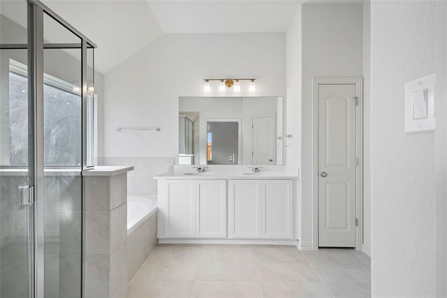 Bathroom featuring a shower stall, a bath, double vanity, light tile patterned floors, and a closet Bathroom featuring a shower stall, a bath, double vanity, light tile patterned floors, and a closet