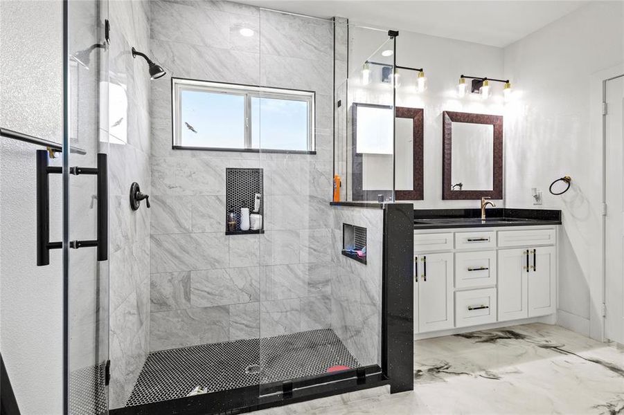 Full bath with a shower stall, vanity, and light marble finish floors Full bath with a shower stall, vanity, and light marble finish floors