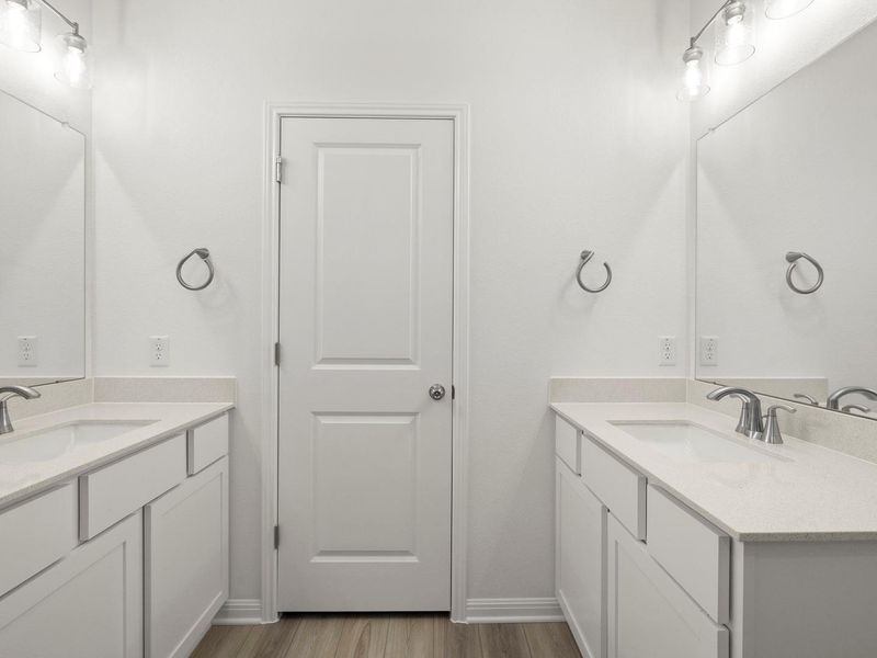 Two individual vanity sinks with sleek countertops and mirrors define this well-appointed bath space.