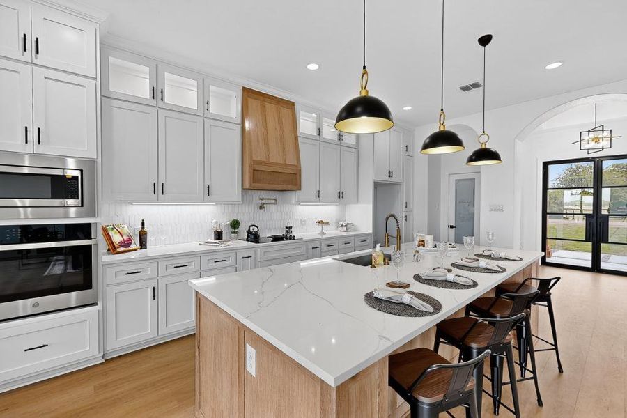Kitchen with appliances with stainless steel finishes, light wood-style flooring, recessed lighting, a center island with sink, and white cabinets