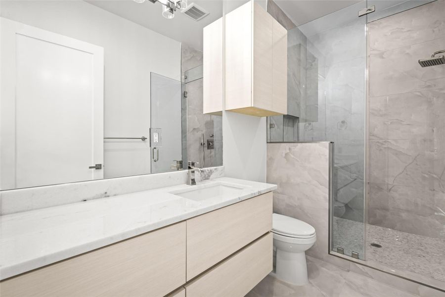 The ensuite bathroom features a modern floating vanity, an oversized walk-in shower with built-in bench, all highlighted w/ polished nickel hardware & fixtures The ensuite bathroom features a modern floating vanity, an oversized walk-in shower with built-in bench, all highlighted w/ polished nickel hardware & fixtures
