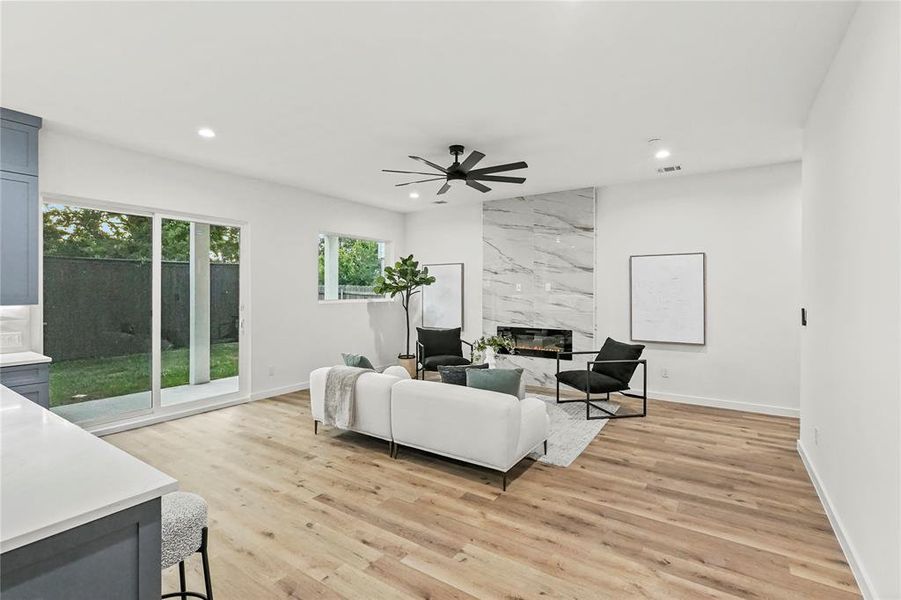 Living room featuring ceiling fan, light wood-type flooring, and a high end fireplace