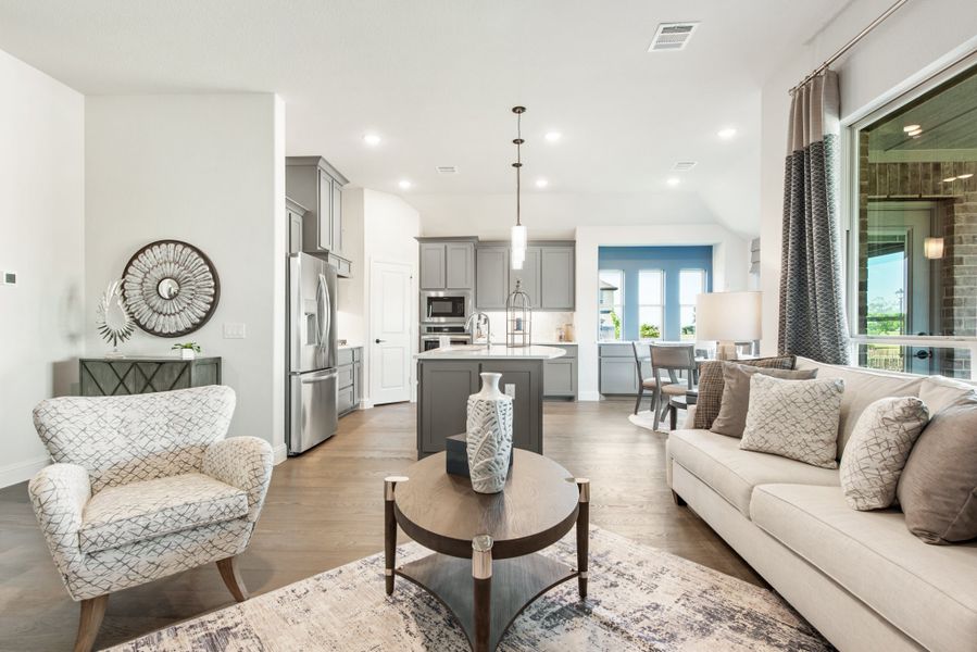 Open-concept living room with hardwood floors flowing into kitchen with gray cabinets and center island