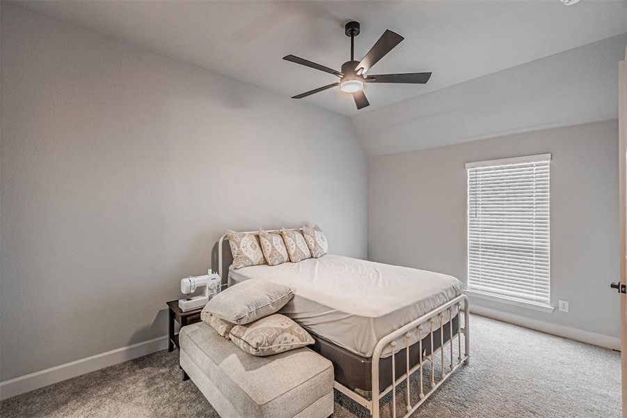 Carpeted room featuring a window with blinds, a modern ceiling fan with lighting, light-colored walls, and a door with dark hardware