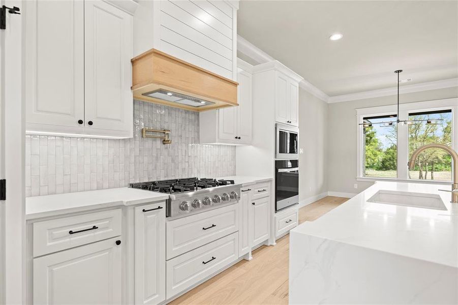 Kitchen featuring decorative backsplash, white cabinetry, light stone countertops, stainless steel appliances, and light wood-type flooring Kitchen featuring decorative backsplash, white cabinetry, light stone countertops, stainless steel appliances, and light wood-type flooring