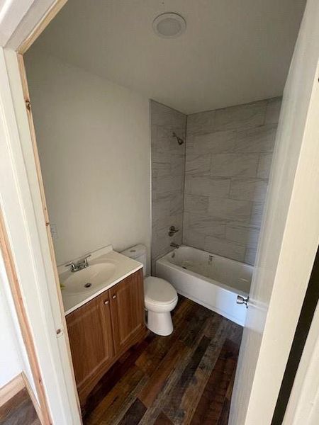Bathroom with vanity, toilet, wood finished floors, and tub / shower combination