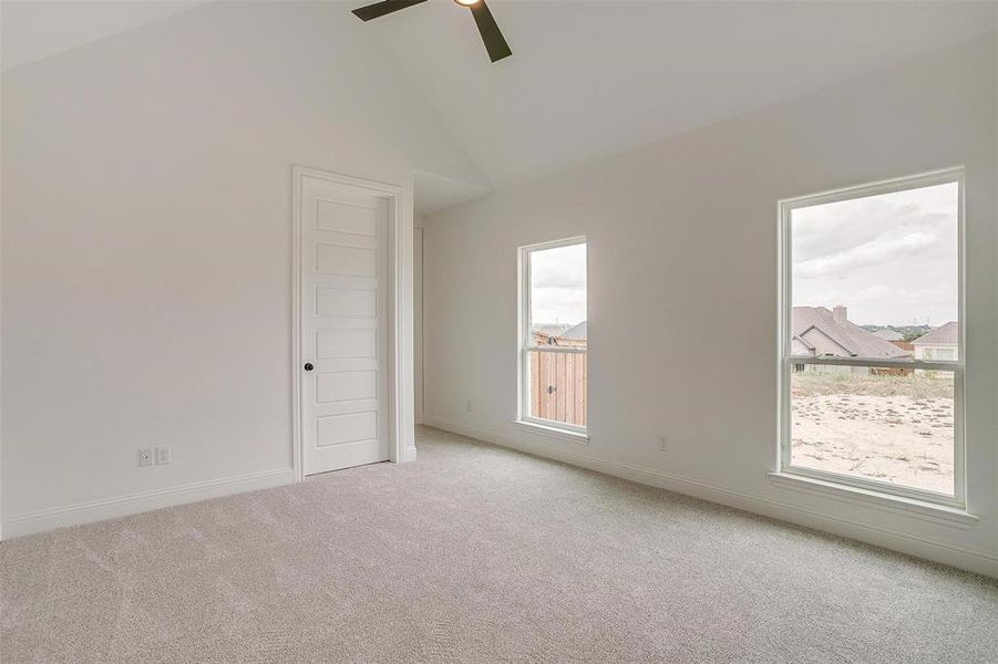 Carpeted empty room featuring ceiling fan and high vaulted ceiling