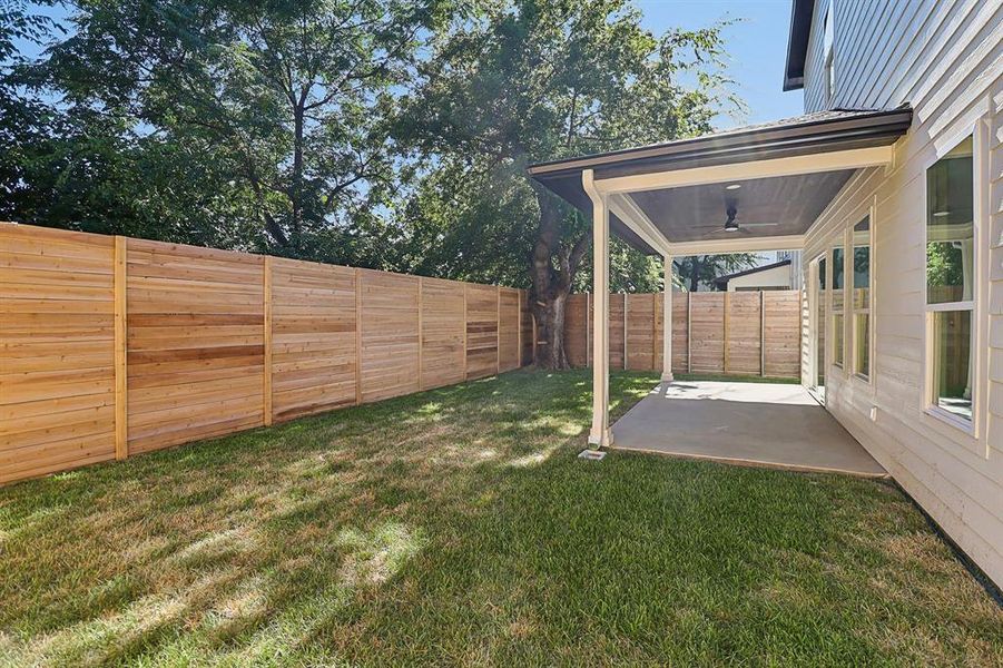 Fenced backyard featuring a ceiling fan and a patio area
