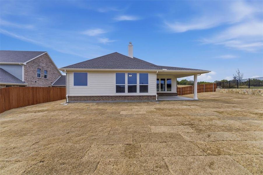 Back of property with a patio, a fenced backyard, a chimney, brick siding, and a shingled roof