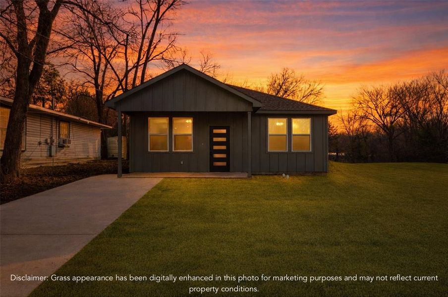 View of front of home with board and batten siding, a front yard, driveway, and covered porch
