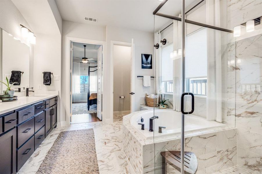Ensuite bathroom featuring a garden tub, double vanity, a marble finish shower, ceiling fan, and light marble finish floors