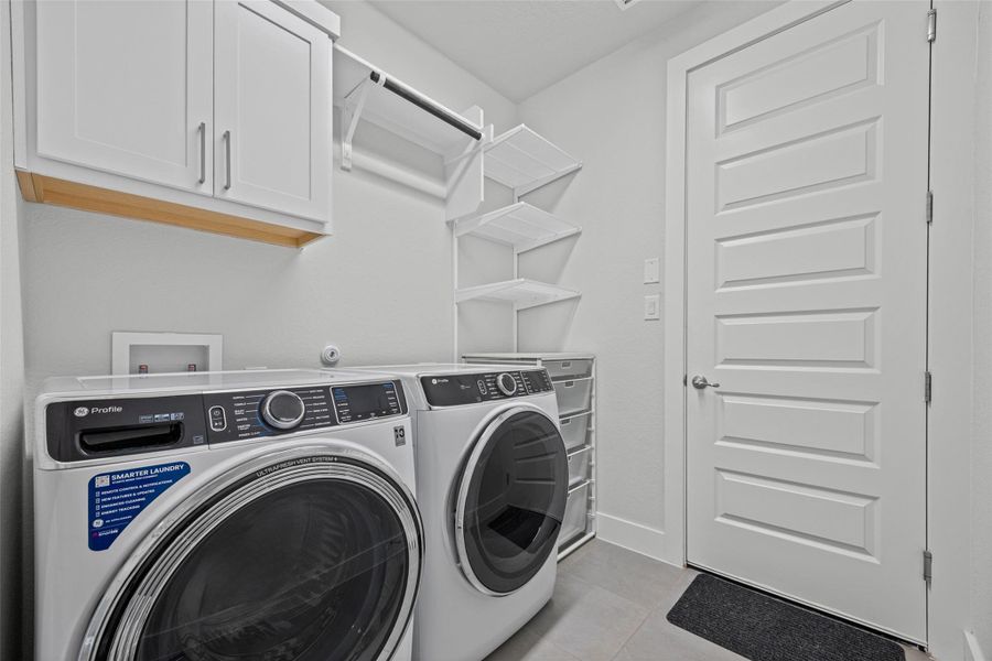 A well-appointed utility room featuring a washer and dryer, complemented by organized storage shelves and cabinetry.