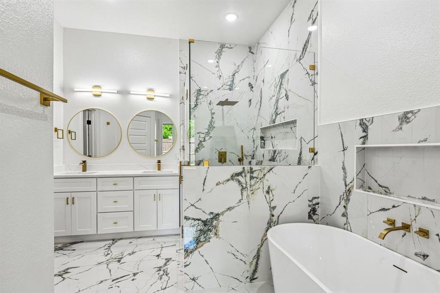 Luxury bathroom featuring a freestanding soaking tub with a wall-mounted brass faucet