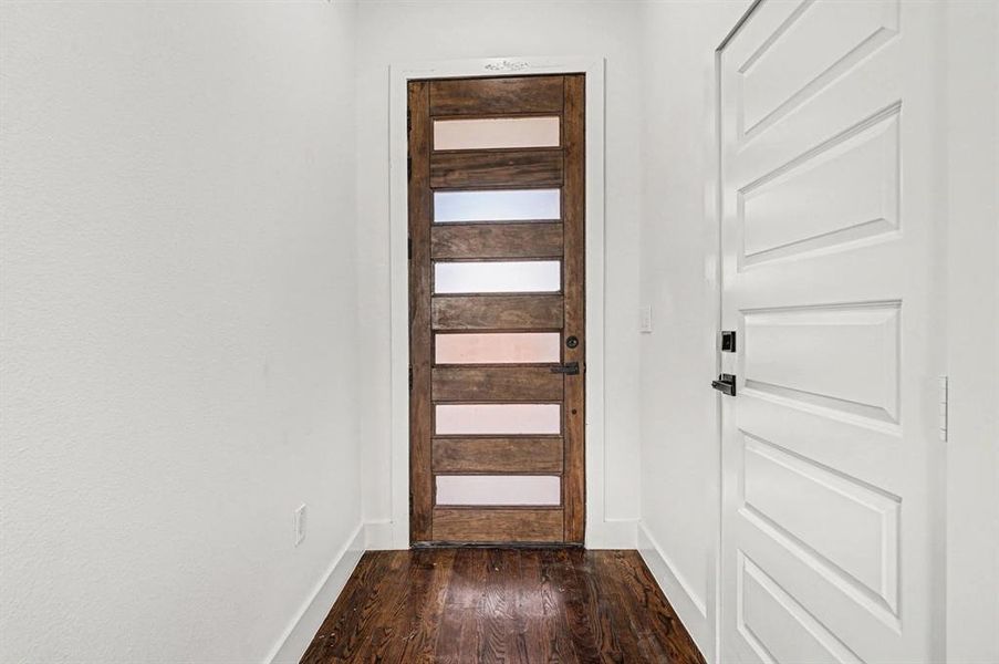Entryway featuring baseboards and hardwood flooring.  Elegant front door with frosted glass panes for ambient light.
