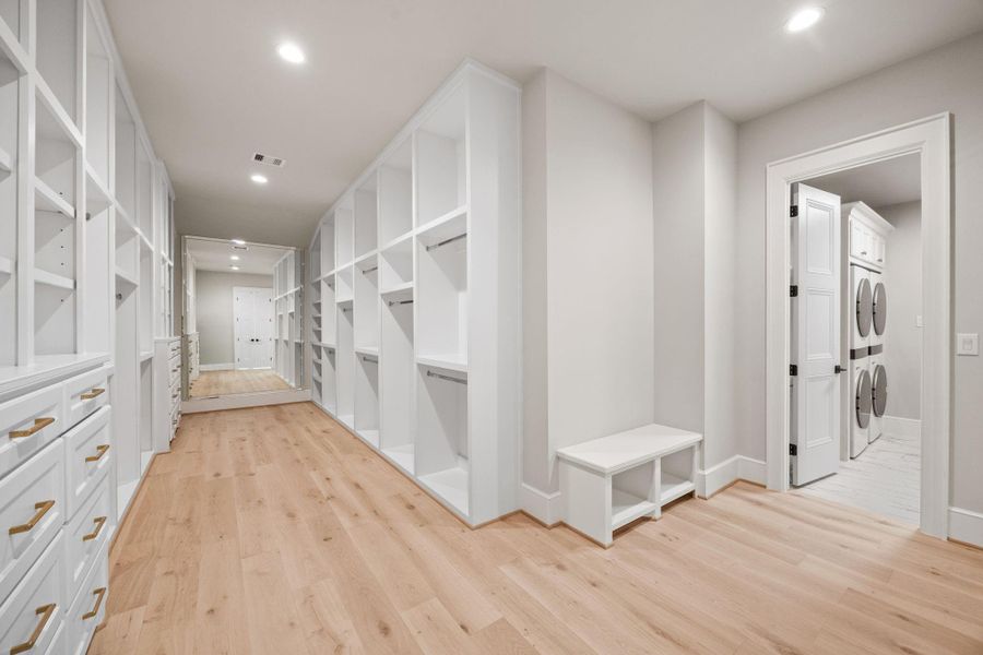 HUGE PRIMARY WALK-IN CLOSET. Features include Custom site built wardrobe w/ chrome clothing bars, 2 full length mirrors, bench w/ shoe cubbies & direct entrance into Laundry Room which has TWO SETS of W/D included with the home.