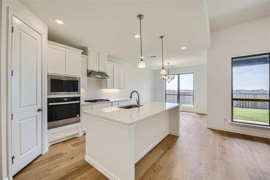 Kitchen featuring hanging light fixtures, a center island with sink, light wood-type flooring, appliances with stainless steel finishes, and sink