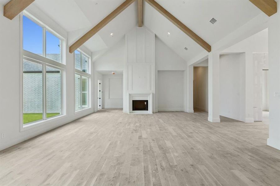 Natural light fills the great room with a cathedral ceiling displaying beautiful wood beams, two-story fireplace, and floor to ceiling windows overlooking your outdoor retreat.