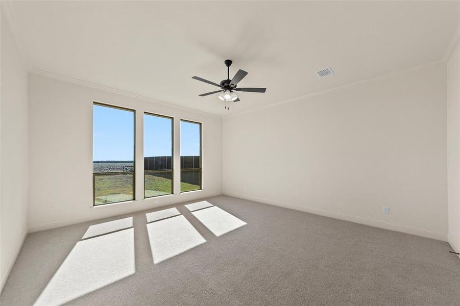 Empty room featuring light colored carpet, ornamental molding, and ceiling fan Empty room featuring light colored carpet, ornamental molding, and ceiling fan