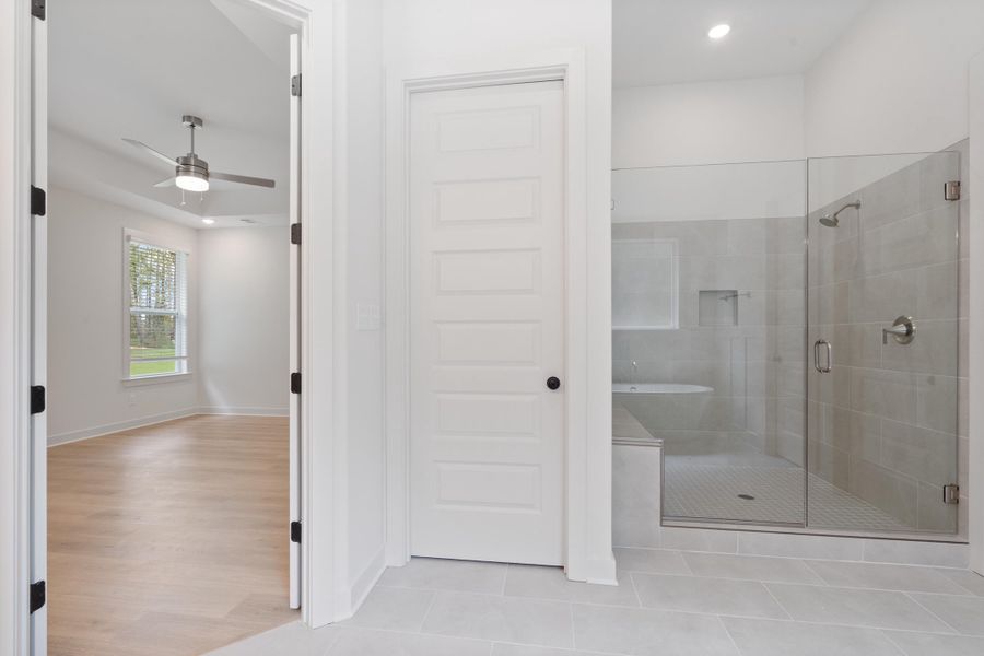 Spacious bathroom featuring a glass-enclosed shower, built-in shower bench, and light-toned tile flooring Spacious bathroom featuring a glass-enclosed shower, built-in shower bench, and light-toned tile flooring